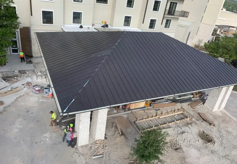 Metal roofing installation team working on a commercial building in Asbury